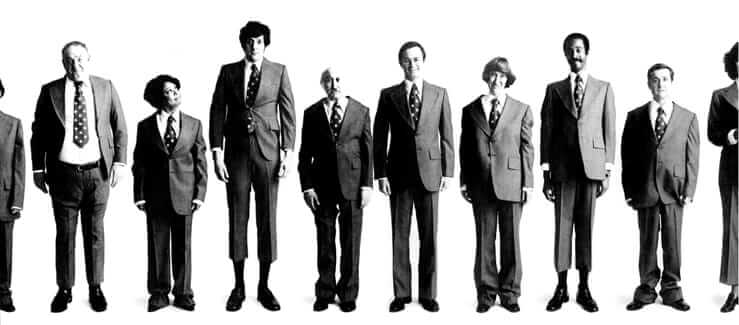 Men standing in a row dressed in the same suit.