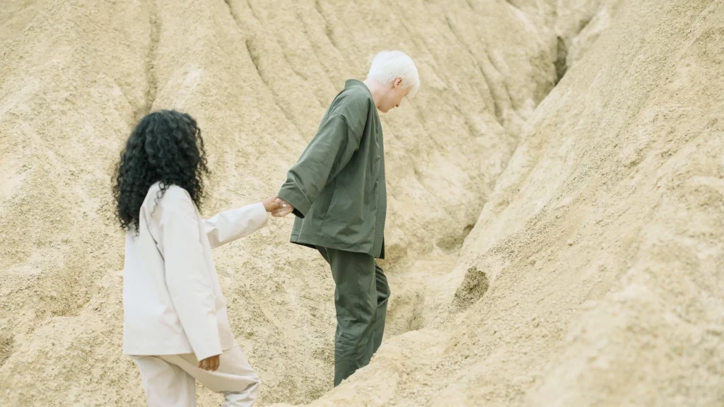 A couple holding hands, traversing a trail.